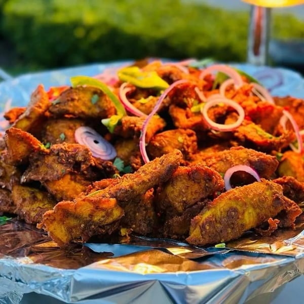 Close-up of Zaffron's fried Afghan potatoes with red onions and green peppers on foil.
