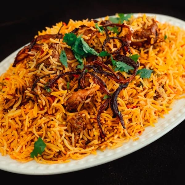 A large platter of Zaffron's chicken biryani, garnished with cilantro and crispy fried onions.